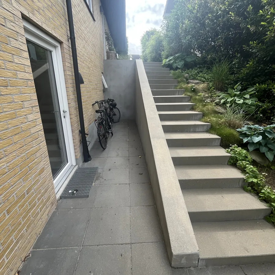 Betonmur langs en trappe ved huset, før beklædning