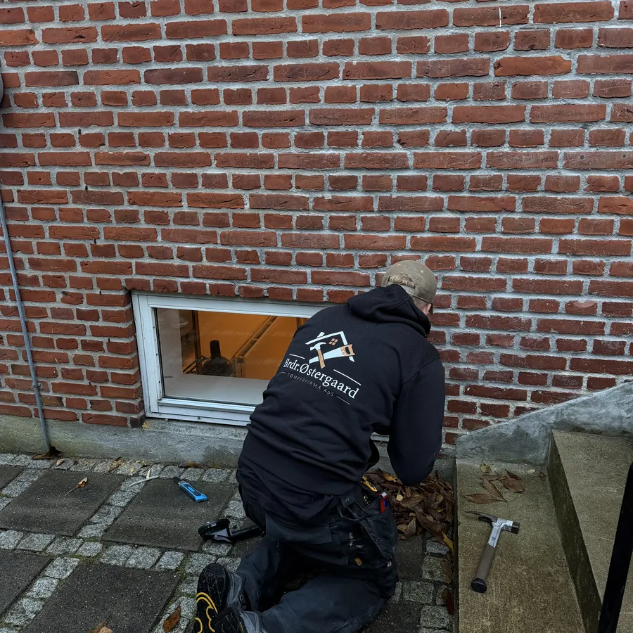 Victor arbejder ved kældervinduet, set bagfra